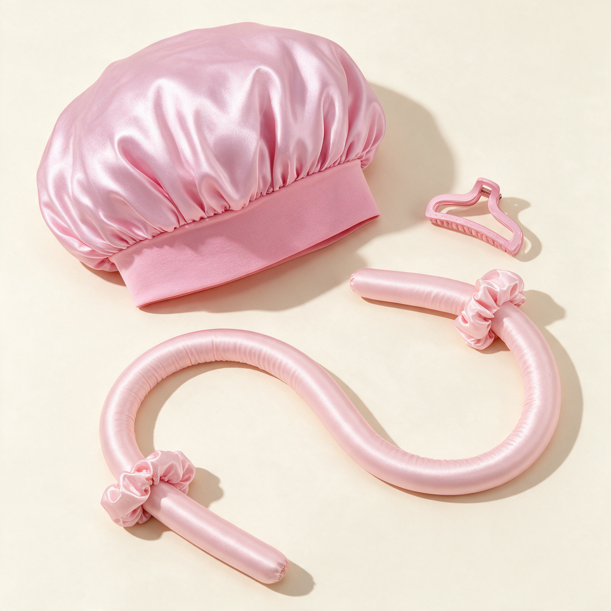 Coffret Nuit Sans Chaleur rose : bonnet satin, ruban boucleur, deux chouchous et pince, à plat sur fond crème
